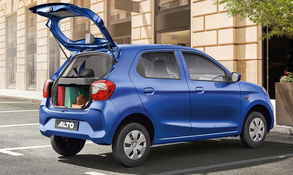 Suzuki Alto con el baúl abierto con maletas y paquetes dentro, estacionado.