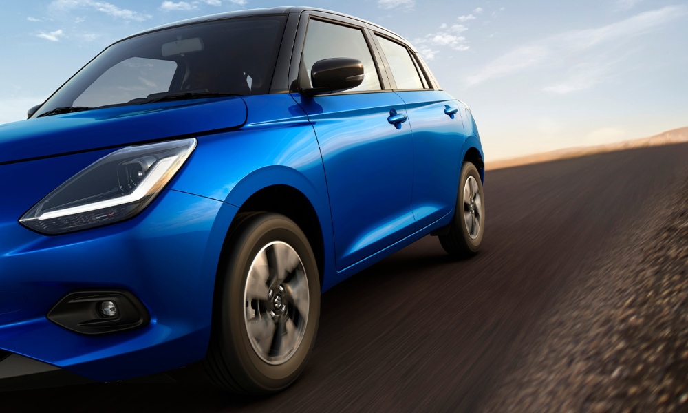 Suzuki Swfit Smart Hybrid color azul siendo conducido sobre terreno rocoso.
